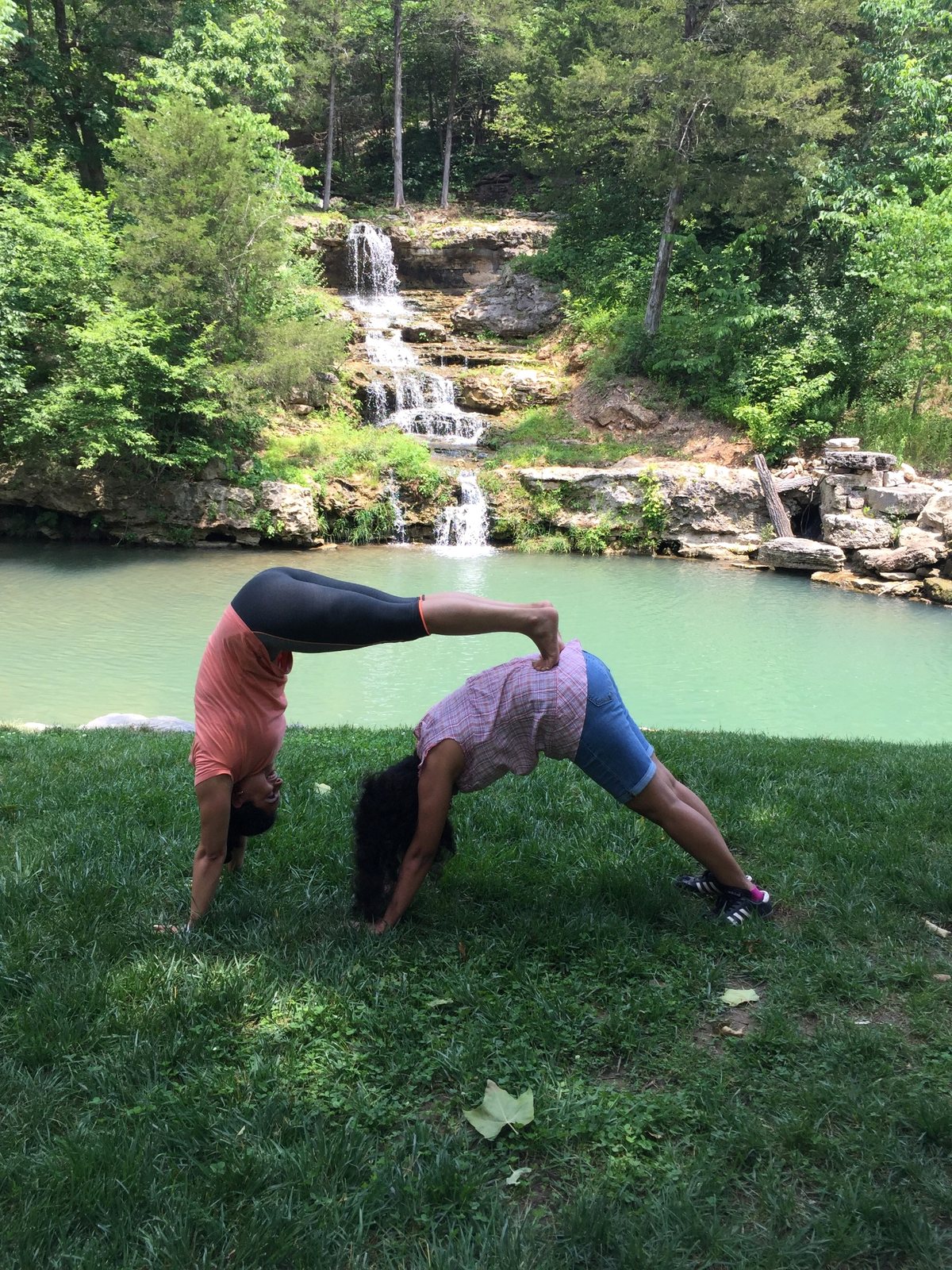 Outdoor partner yoga practice near a waterfall